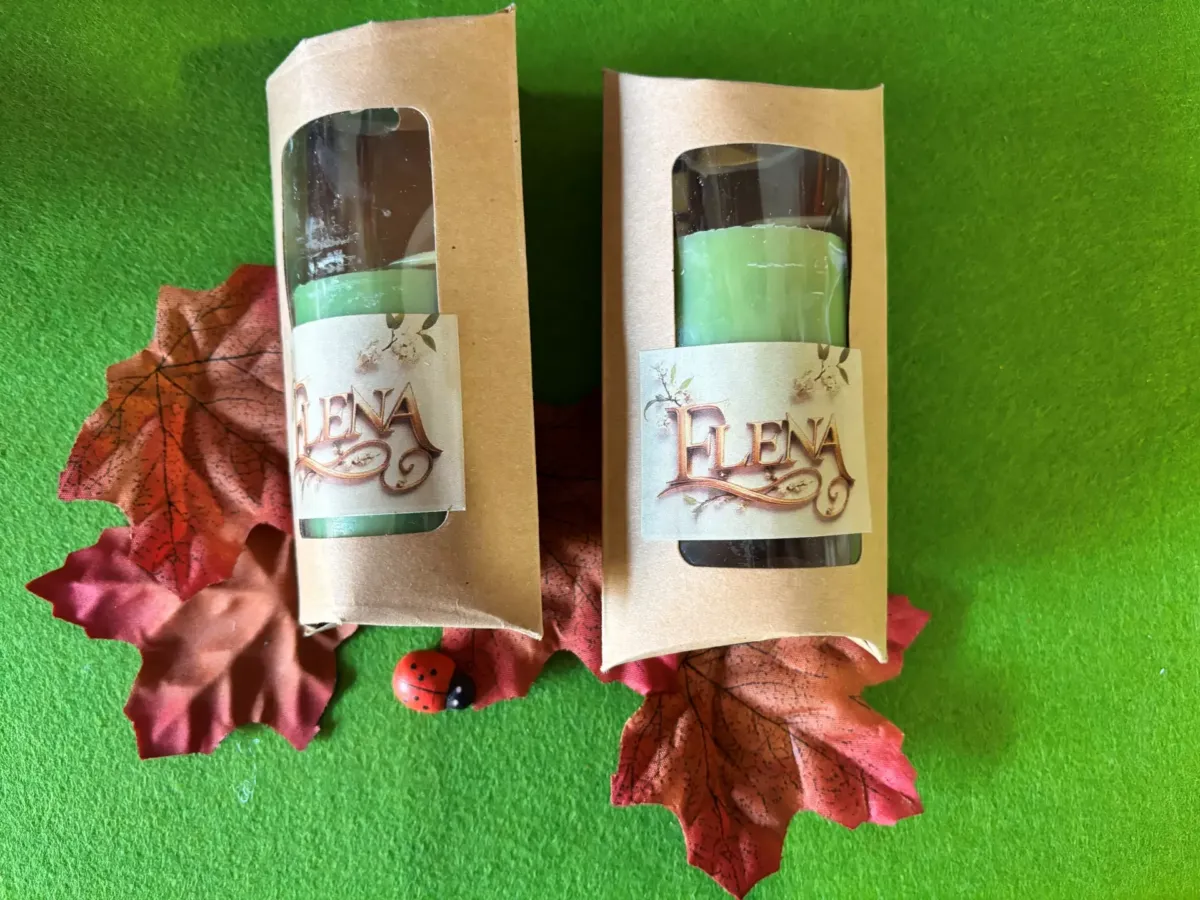 Dos velas verdes en embalaje sobre hojas rojas